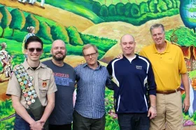 Collaborators posing in front of mural