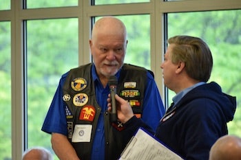 Person holding microphone for veteran to speak.