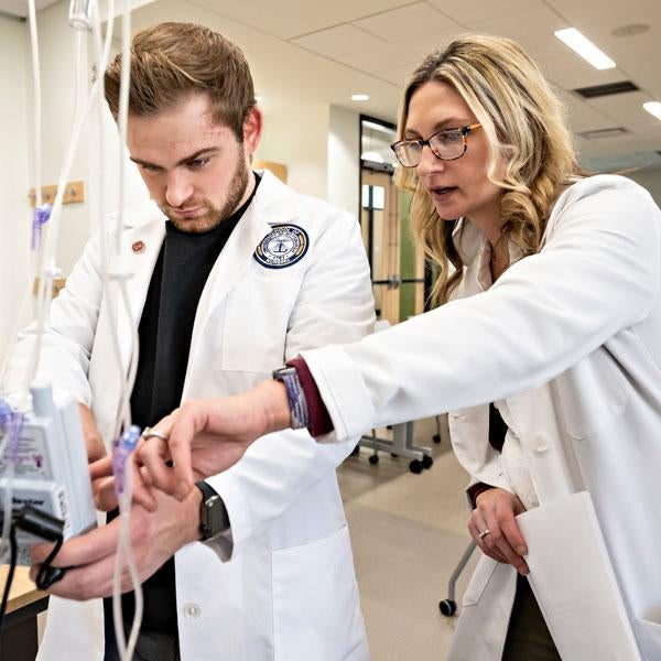 A nursing instructor works with a student.