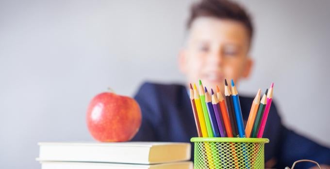 student sitting behind books and pencils