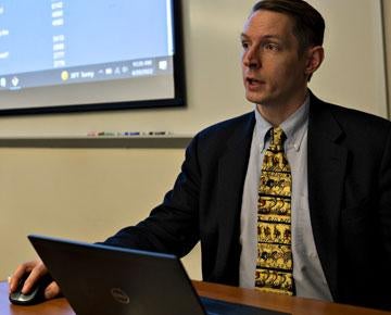 Faculty member seated using laptop